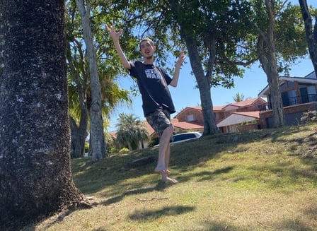 A young man dances with joy outside