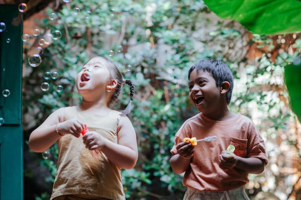 Down syndrome disability child girl boy diverse bubbles happy fun friends outside