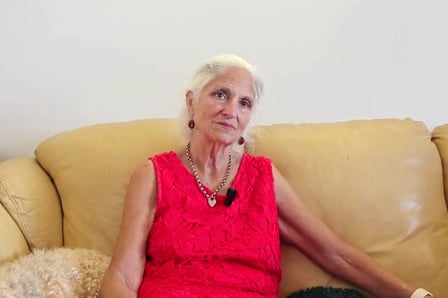 An elderly woman sitting in comfortable conversation in an indoor setting