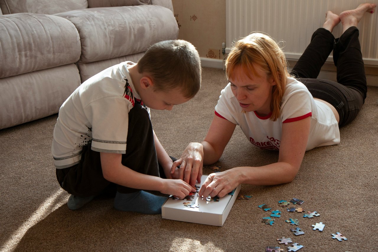 A white woman and child working on a puzzle together in a home setting