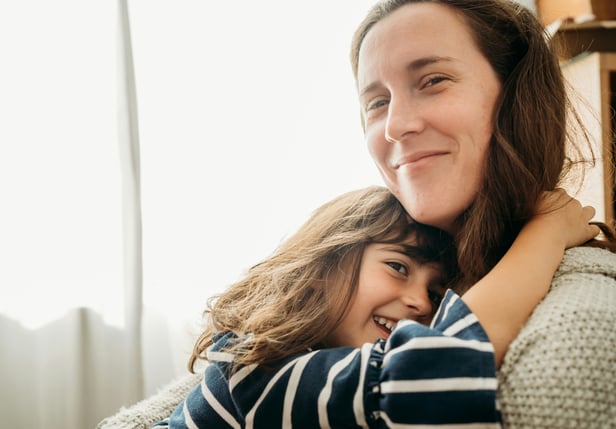 white mum and daughter hug smiling in home setting